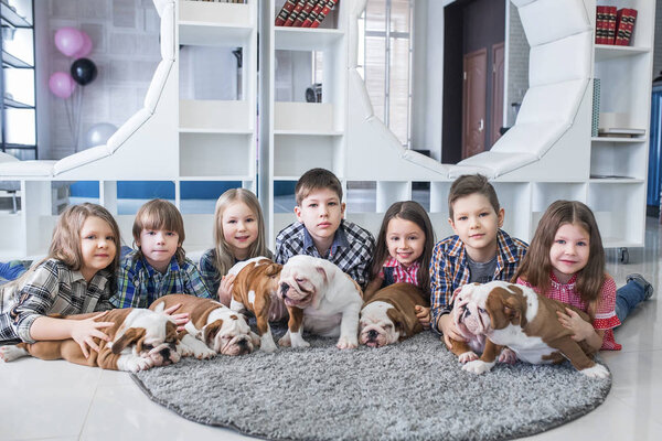 Cute kids lying on the floor with the puppies English bulldog
