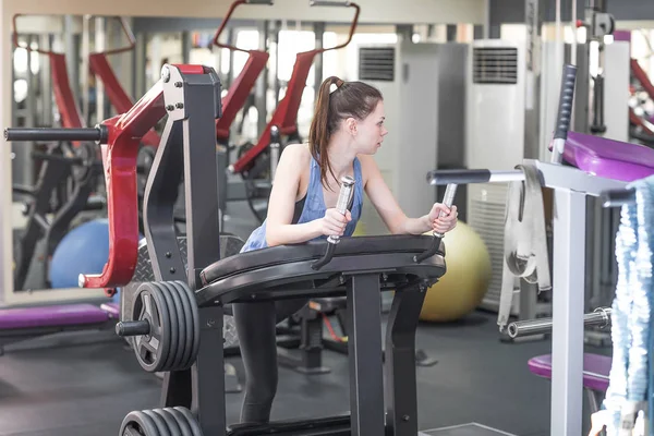 Jonge vrouw werken haar quads bij machine pers in de sportschool — Stockfoto