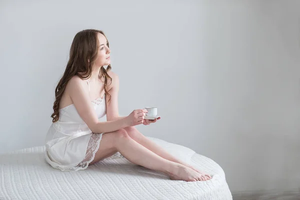Meisje met kopje koffie in de slaapkamer — Stockfoto