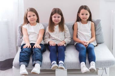 Kanepe ve dostluk kavramı üzerinde oturan üç mutlu kız portresi