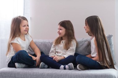 Kanepe ve dostluk kavramı üzerinde oturan üç mutlu kız portresi