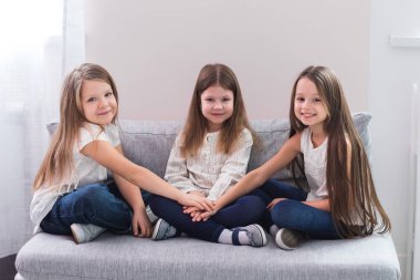 Kanepe ve dostluk kavramı üzerinde oturan üç mutlu kız portresi