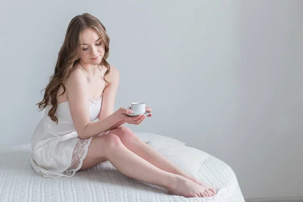 Meisje met kopje koffie in de slaapkamer — Stockfoto