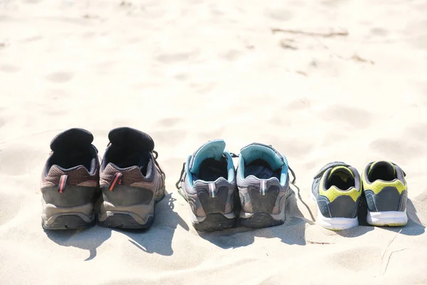 Три пары кроссовок на песке. Концепция выходных — стоковое фото