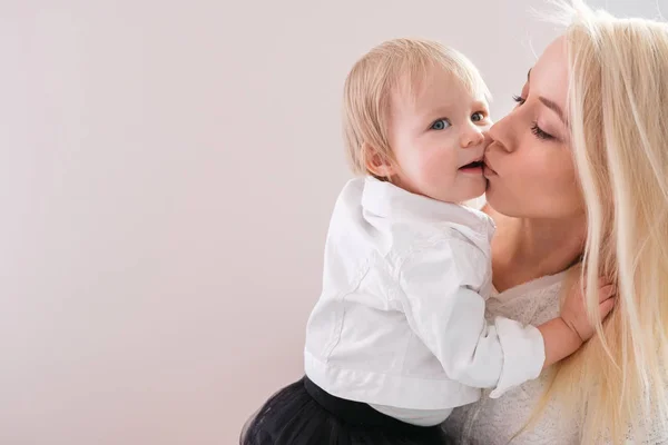 Молодая мать держит на руках маленькую дочь и целует ее в детской. — стоковое фото