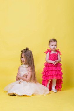 Elbiseler sarı bir arka plan üzerinde iki kız kardeş farklı yönde bak ve rahatsız