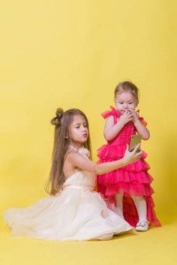 Elbiseler sarı bir arka plan üzerinde iki kız kardeş kendilerini telefonla fotoğrafı