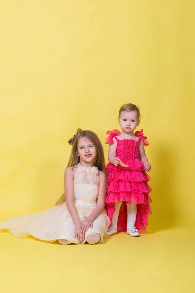 Zwei Schwestern in Kleidern auf gelbem Hintergrund im Atelier — Stockfoto