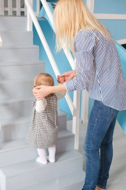 Genç güzel mutlu anne kızı onun ilk adım yaparken yardım