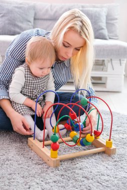 Çocuk kız eğitici oyuncak kapalı oynuyor. Mutlu anne akıllı kızı arıyorum