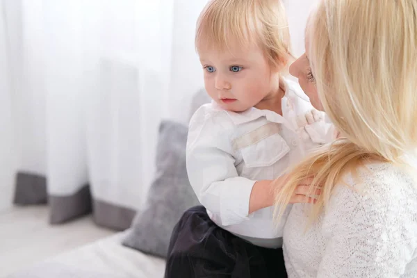 Ung mamma hålla en baby dotter i hennes armar och kysser henne i barnkammaren — Stockfoto