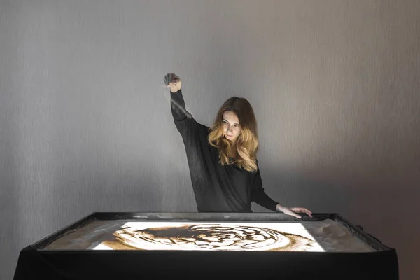 Kadın kum, kum animasyon üzerinde çizer, onun elinden kum dökme