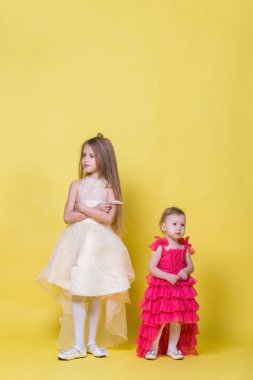 Elbiseler sarı bir arka plan üzerinde iki kız kardeş farklı yönde bak ve rahatsız