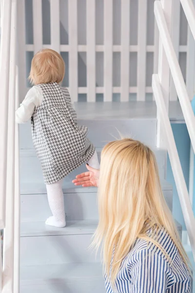 Genç güzel mutlu anne kızı onun ilk adım yaparken yardım