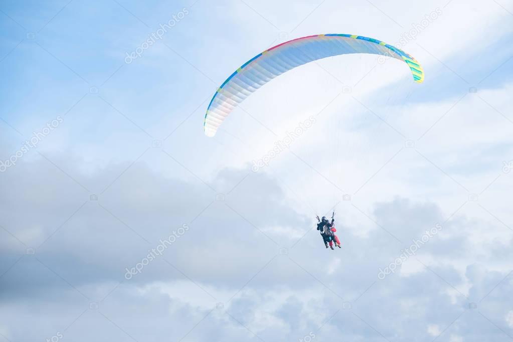 Paragliders in bright blue sky, tandem of instructor and beginner