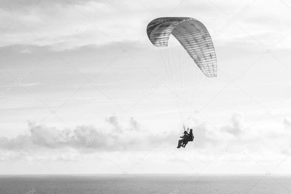 Flying a tandem paraglider over the sea with views of the horizon