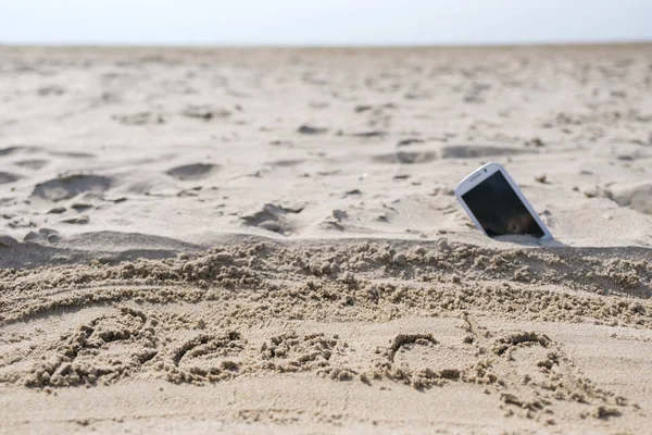 Mobile touch phone in sand on a beach