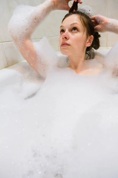 Молодая красивая брюнетка принимает ванну с пеной — стоковое фото