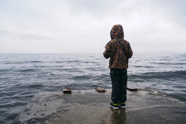 Kleiner Junge blickt im Winter von Seebrücke auf das Meer — Stockfoto