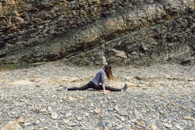 Germe ve bir rock platform üzerinde egzersiz sağlıklı Olgun kadın figürü yan görünüm