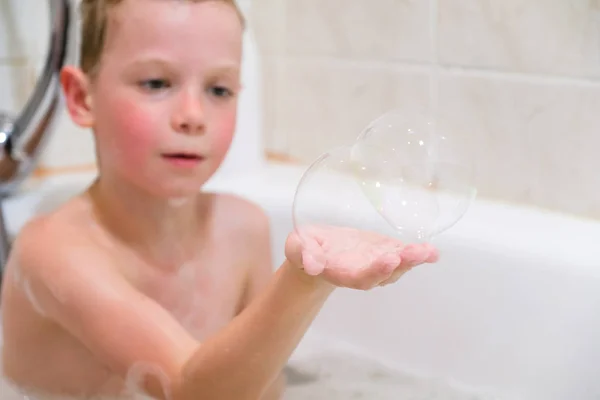 Ребенок играет в ванне с мыльными пузырями дома — стоковое фото