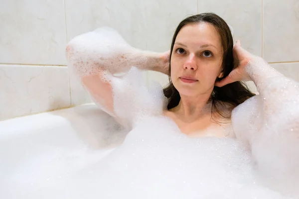 Jovem bela morena mulher toma banho de espuma — Fotografia de Stock