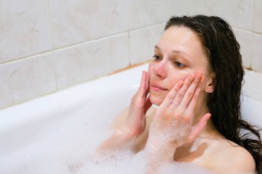 Güzel kadın yüzü beyaz banyo üzerinde köpük tedavisi ile Temizleme