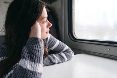 Trende oturan ve pencereden dışarı bakıyor güzel kız