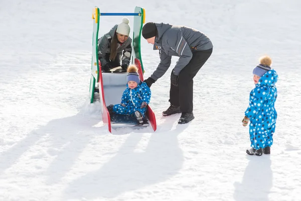 Irmão gêmeo rola para baixo colina, feliz família passeios de inverno no parque — Fotografia de Stock