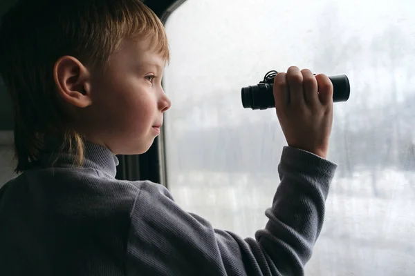 Liten pojke tittar genom fönstret. — Stockfoto