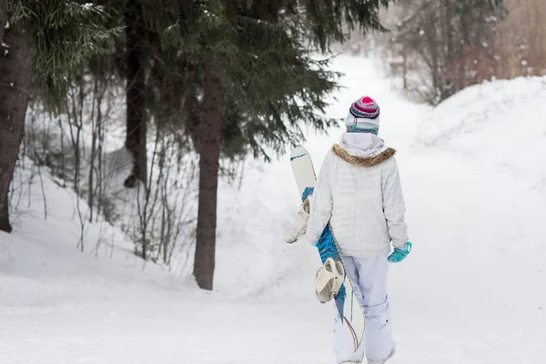 Niña snowboarder bajando en una montaña nevada en el bosque — Foto de Stock