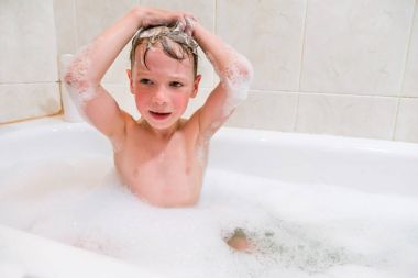 küçük bir çocuk banyoda saç yıkıyor