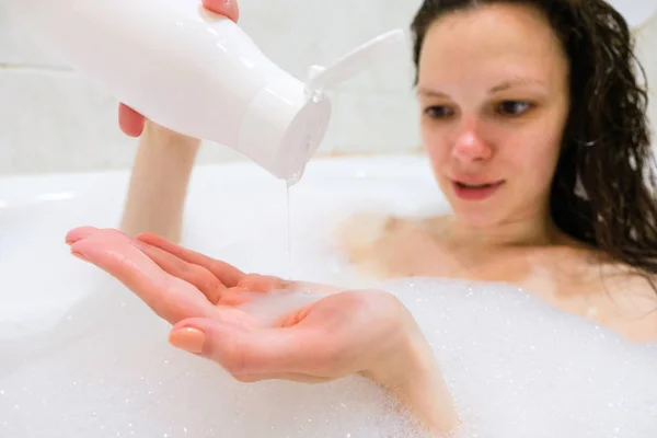 Brunette woman pouring shampoo on hand in shower — Stock Photo, Image
