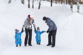 Otec, matka a děti, dvojčata hold každý druhý ruce a chůzi na sněhu