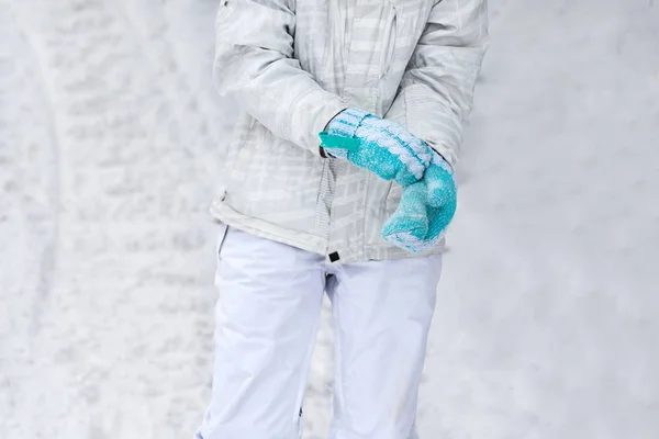 Молода дівчина сноубордист носить рукавички на руках на сніговому схилі — стокове фото