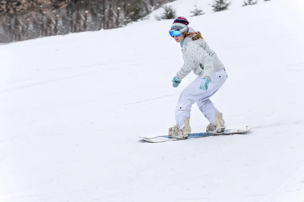 Jeune femme snowboarder en mouvement sur snowboard en montagne — Photo