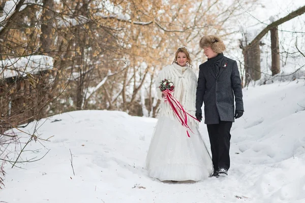 Jeune couple de jeunes mariés marchant dans une forêt d'hiver dans la neige . — Photo