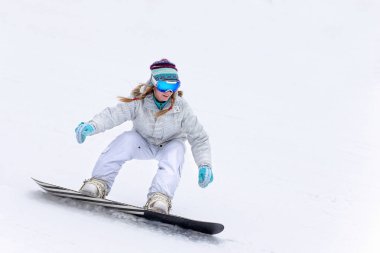 Genç kadın snowboardcu dağlarda snowboard yapıyor.