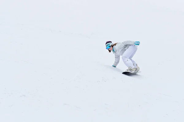 Young woman snowboarder in motion on snowboard in mountains — Stock Photo, Image