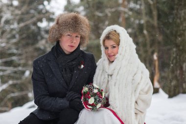 Gelin ve damat köpek kış manzara arka plan üzerinde oturan, şık güzel genç Çift