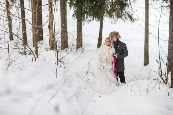 Jeune couple de jeunes mariés marchant dans une forêt d'hiver dans la neige . — Photo