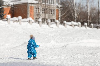 Bir çocuk tek başına parkta bir kış gününde yürür.
