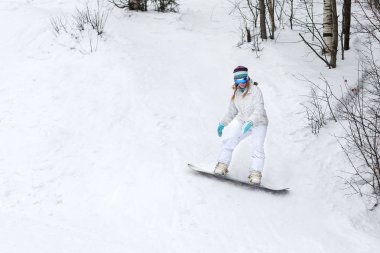 Genç kadın snowboardcu dağlarda snowboard yapıyor.