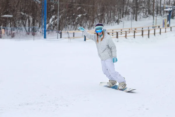 Jeune femme snowboarder en mouvement sur snowboard en montagne — Photo