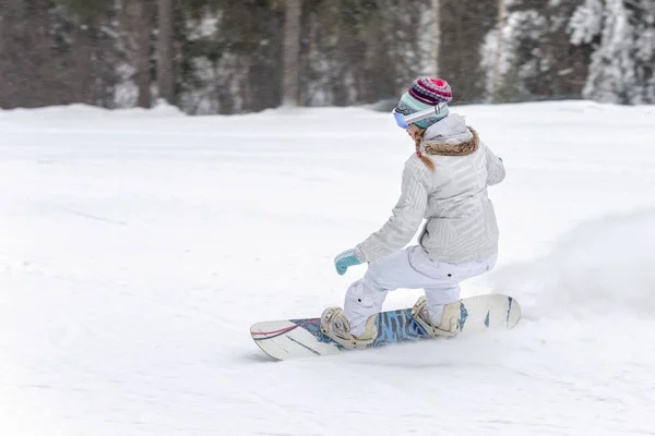 Νεαρή γυναίκα snowboarder σε κίνηση σε snowboard στα βουνά — Φωτογραφία Αρχείου