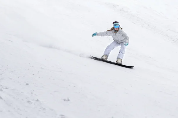 Young woman snowboarder in motion on snowboard in mountains — Stock Photo, Image