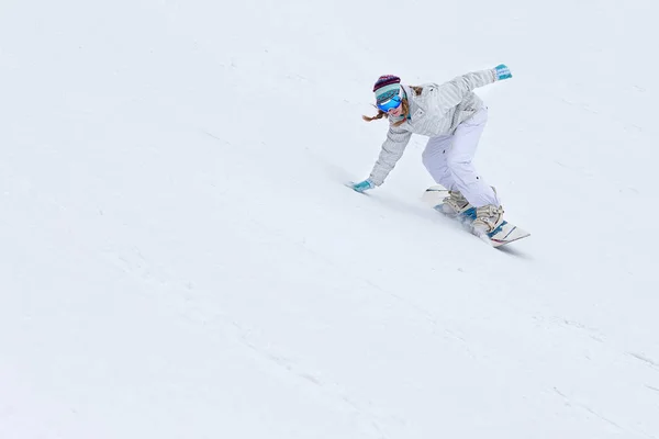 Junge Snowboarderin auf Snowboard in den Bergen in Bewegung — Stockfoto