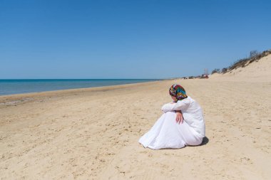Genç kadın uzak denizde kıyıya otururken arıyor