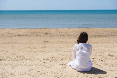 Lobg saçlı bir plajda ve denizde seyir yalnız esmer kadın. Arkadan Görünüm.