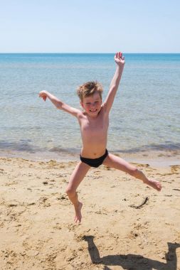 Altı yaşında çocuk siyah speedo gülüyor ve deniz atlama.